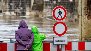 Ein Schild warnt an der Steinernen Brücke vor dem Hochwasser der Donau. — © Armin Weigel/dpa