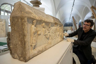 Augsburgs Stadtarchäologe Sebastian Gairhos zeigt ein römisches Grabrelief, das Ende des Jahres bei einer großen Ausstellung in Rom präsentiert werden soll. (Archivbild) — © Stefan Puchner/dpa