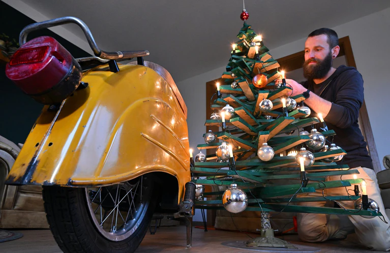 Jan Hofmann schmückt einen Weihnachtsbaum auch mit Weihnachtsbaumkugeln aus Simson-Blinkern. — © Martin Schutt/dpa