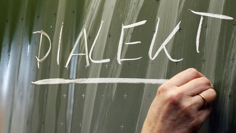 Das Wort «Dialekt» steht auf einer Tafel. — © Daniel Karmann/dpa