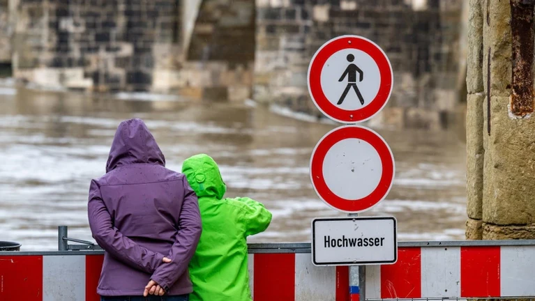 Ein Schild warnt an der Steinernen Brücke vor dem Hochwasser der Donau. — © Armin Weigel/dpa