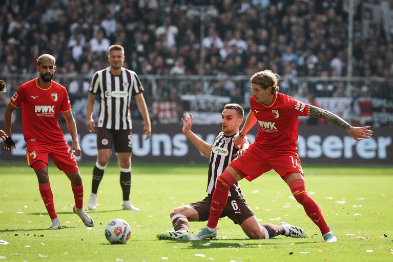 Im Zweikampf: Kristijan Jakić vom FC Augsburg (r) und St. Paulis James Sands. — © Christian Charisius/dpa