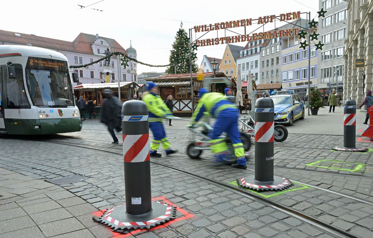 Zu den Hauptverkehrszeiten müssen Sicherheitsmitarbeiter neben dem Augsburger Christkindlesmarkt jede Stunde dutzendfach schwere Poller bewegen, damit die Straßenbahnen durchfahren können. — © Malin Wunderlich/dpa