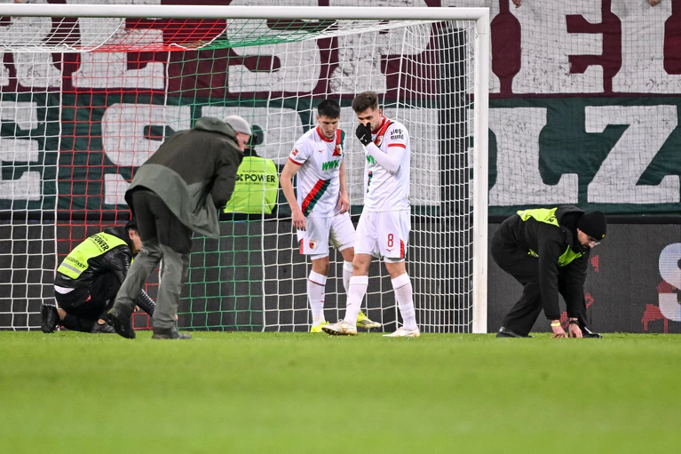 Spieler und Ordner sammeln nach dem Fanprotest Gegenstände vom Rasen. — © Harry Langer/dpa