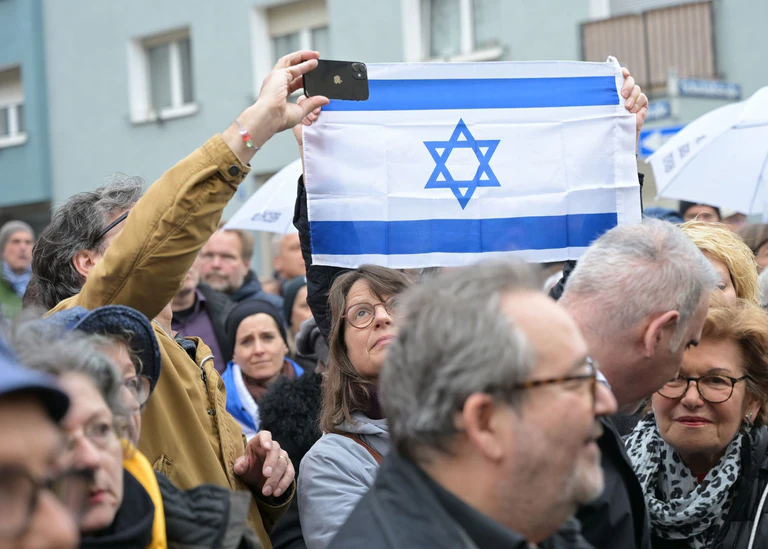Demonstranten halten ein Transparent mit dem Davidstern hoch.  — © Malin Wunderlich/dpa
