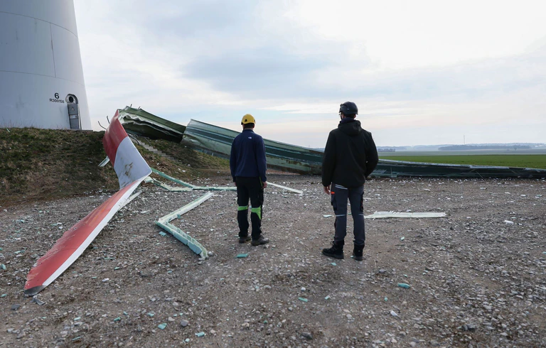 Mitarbeiter besichtigen das von einem Windrad abgebrochene Rotorblatt. — © Daniel Löb/dpa