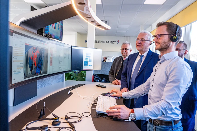 Innenminister Joachim Herrmann (2.v.r.) lässt sich von Fabian Ripke (rechts) die Arbeit des Telenotarztes erläutern. Mit im Bild ist Josef Laumer, Landrat des Landkreises Straubing-Bogen (links). — © Armin Weigel/dpa