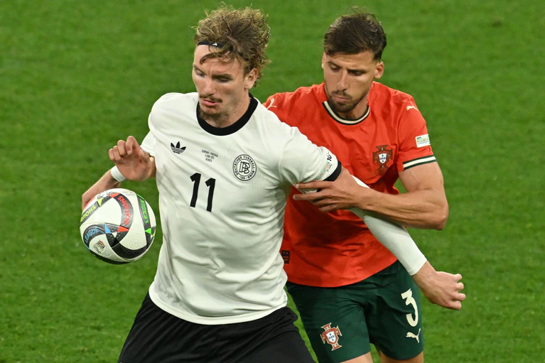 Nick Woltemade (l) hatte bei seinem Länderspiel-Debüt gegen Portugals Abwehrrecken einen schweren Stand. — © Peter Kneffel/dpa
