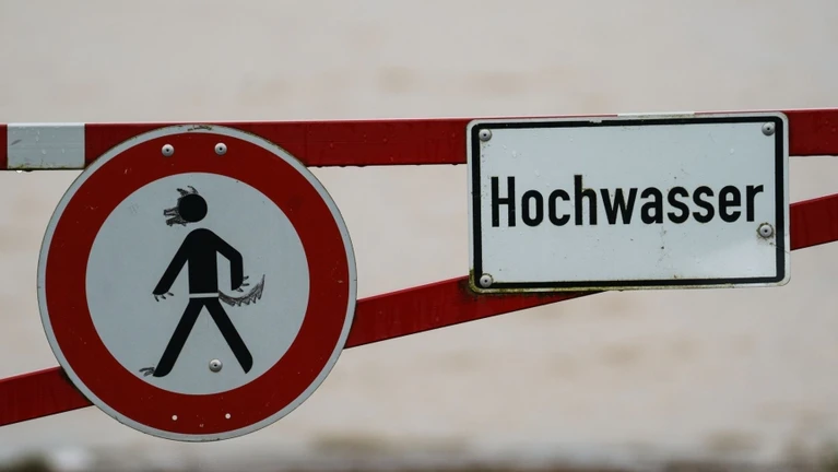 Ein Hochwasser-Schild steht an einem überfluteten Feld. — © Andreas Arnold/dpa/Symbolbild