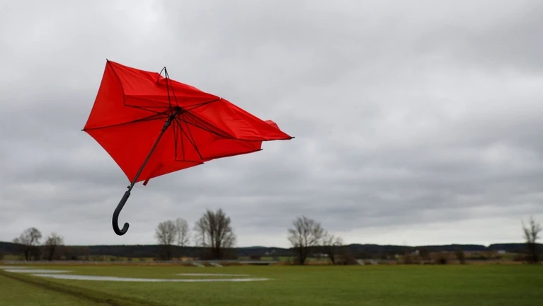 Ein kaputter Regenschirm fliegt im Wind von Sturmtief «Zoltan» über eine Wiese. — © Thomas Warnack/dpa