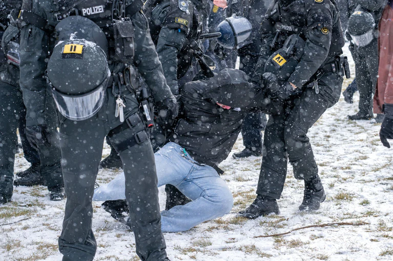 Polizisten bringen am Rande einer Demonstration eine Person zu Boden.  — © Pia Bayer/dpa