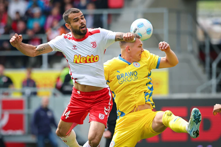 Der Regensburger Robin Ziegele (l) kämpft mit dem Braunschweiger Julian Baas um den Ball. — © Daniel Karmann/dpa