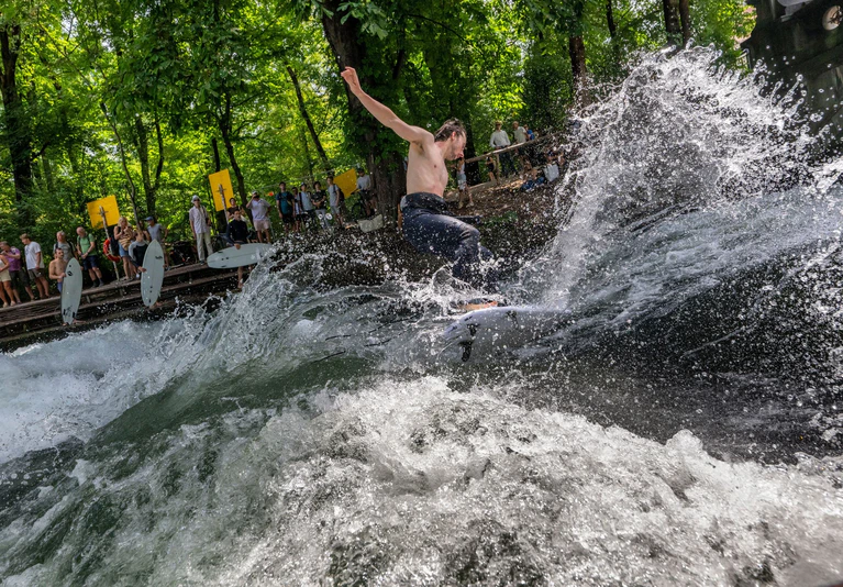 Ab in die erfrischenden Fluten - bei dieser Hitze genießen die Surferinnen und Surfer eine Abkühlung an der Eisbachwelle im Englischen Garten.  — © Peter Kneffel/dpa