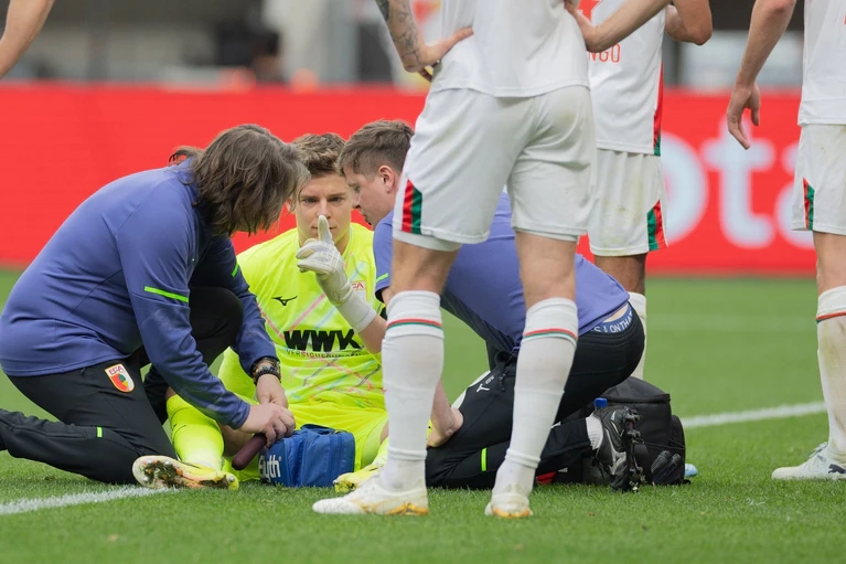 Auch eine kurze Behandlungspause nach einer Abwehr mit dem Kopf konnte Augsburgs Keeper Finn Dahmen nicht aus dem Rhythmus bringen.  — © Rolf Vennenbernd/dpa