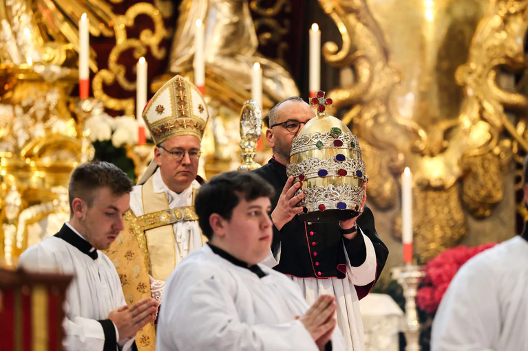In einer Prozession wird die Papstkrone nach der Abnahme zu ihrem vorübergehenden Standort getragen. — © Matthias Balk/dpa