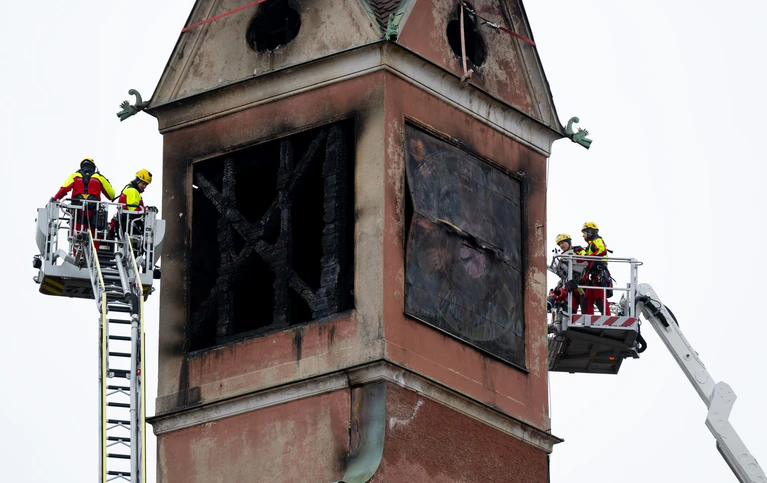 Feuerwehrleute sichern mit Spanngurten lose teile an dem beschädigten Turm des Seniorenheimes.  — © Sven Hoppe/dpa