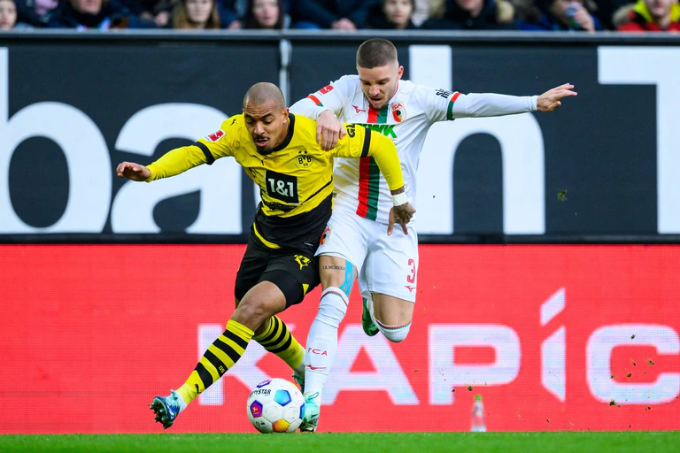Dortmunds Donyell Malen (links) kämpft gegen Augsburg Mads Pedersen um den Ball. — © Tom Weller/dpa