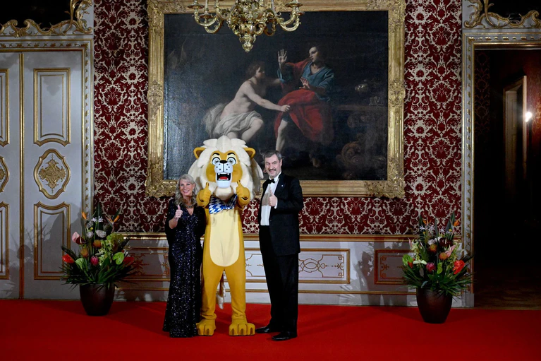Der Bayerische Ministerpräsident Markus Söder und seine Frau Karin Baumüller-Söder zeigen sich mit einem «Löwen» beim Neujahrsempfang des Regierungschefs in der Münchner Residenz beim Defilee. — © Felix Hörhager/dpa