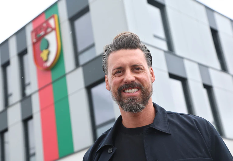 Der neue Trainer Sandro Wagner posiert vor der Geschäftsstelle des FC Augsburg. — © Karl-Josef Hildenbrand/dpa