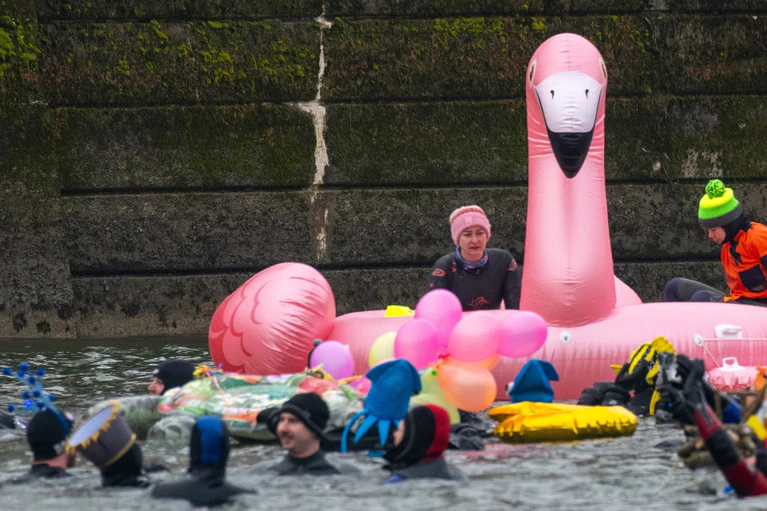 Teils bunt kostümiert schwimmen in und auf der eiskalten Donau Rettungsschwimmer.  — © Stefan Puchner/dpa