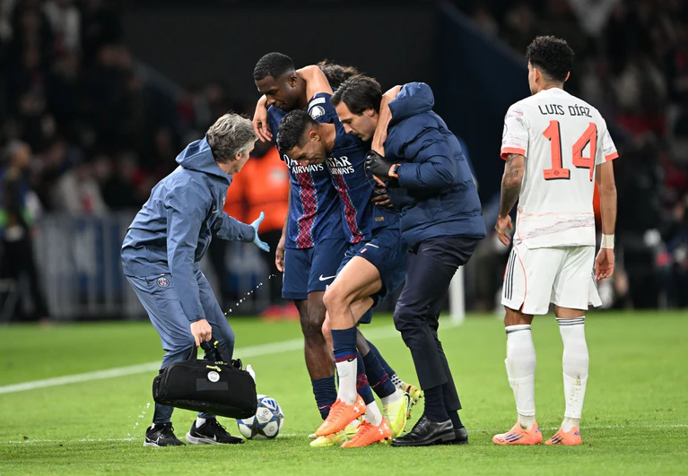 Auf Betreuer gestützt wird der am Fuß verletzte PSG-Spieler Achraf Hakimi (M) vom Platz geführt.  — © Federico Gambarini/dpa