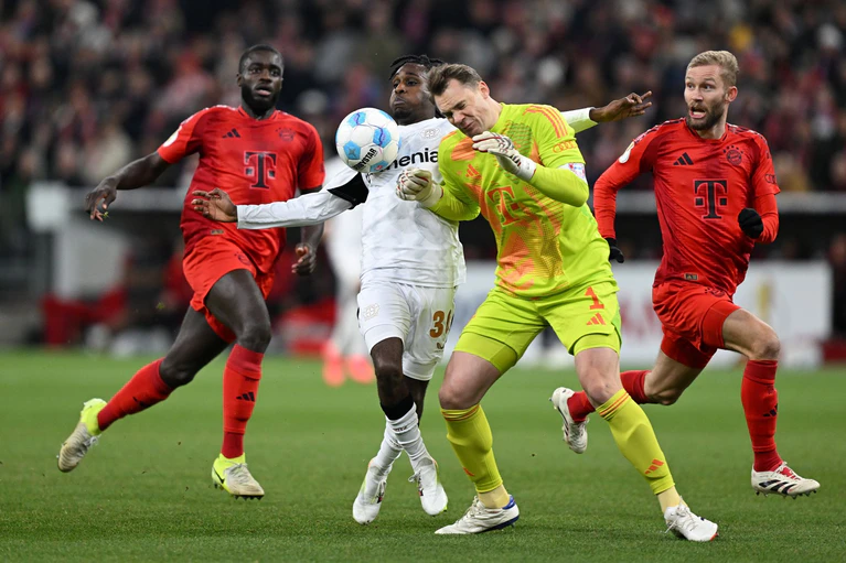 Der folgenschwere Moment: Manuel Neuer (r) kracht mit Leverkusens Jeremie Frimpong zusammen. — © Sven Hoppe/dpa