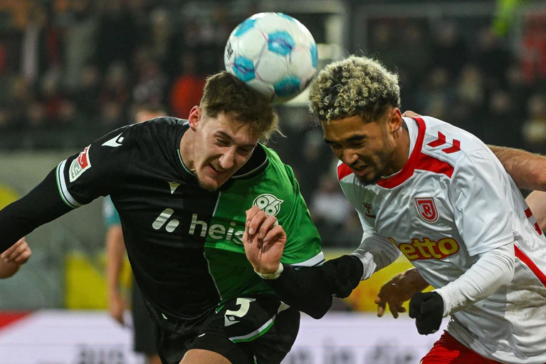 Rasantes Kopfballduell zwischen Hannovers Phil Neumann (l) und Jahn-Profi Bryan Hein. — © Armin Weigel/dpa