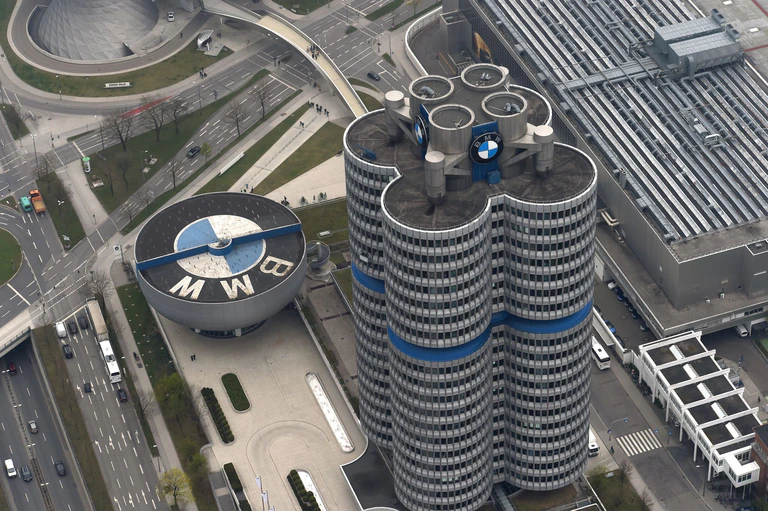 Das Dach des BMW-Museums (l) schmückt das Logo des Autobauers. Es steht direkt neben der Konzernzentrale, dem sogenannten Vierzylinder, vorne im Bild. (Archivbild) — © Felix Hörhager/dpa