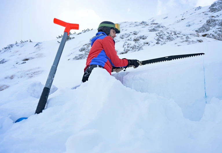 Mit einer Säge schneidet der Lawinenexperte Thomas Feistl einen Block aus dem Schnee, um die Schichten zu analysieren. — © Malin Wunderlich/dpa