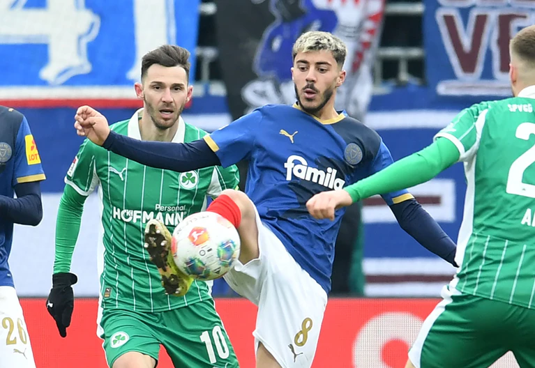 Der Kieler Umut Tohumcu (M) behauptet gegen Branimir Hrgota (l) den Ball. — © Daniel Bockwoldt/dpa