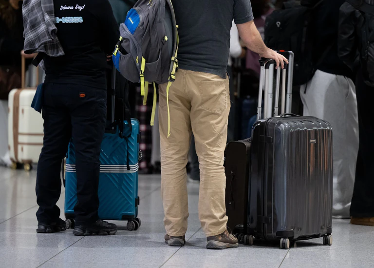 Passagiere stehen am Münchner Flughafen mit ihrem Gepäck an einem Check-in-Schalter. — © Sven Hoppe/dpa