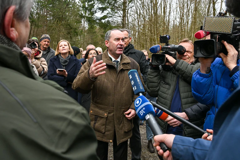 Hubert Aiwanger spricht mit Journalisten und Bürgern im Altöttinger Forst übrer die Windparkpläne. (Archivbild) — © Armin Weigel/dpa
