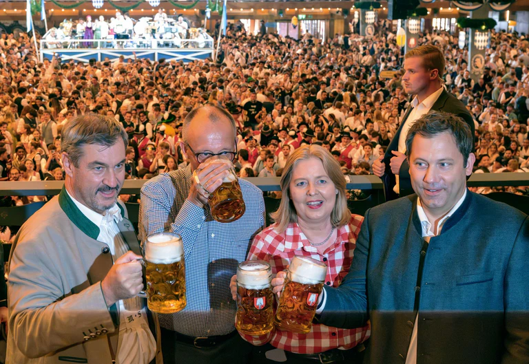 Wenige Tage vor der Veröffentlichung seines Wiesn-Hits «Sweet Caroline» lotste CSU-Chef Markus Söder (links) Kanzler Friedrich Merz (2.v.l.) und das SPD-Führungsduo Bärbel Bas und Lars Klingbeil auf das Oktoberfest. (Archivbild) — © Peter Kneffel/dpa