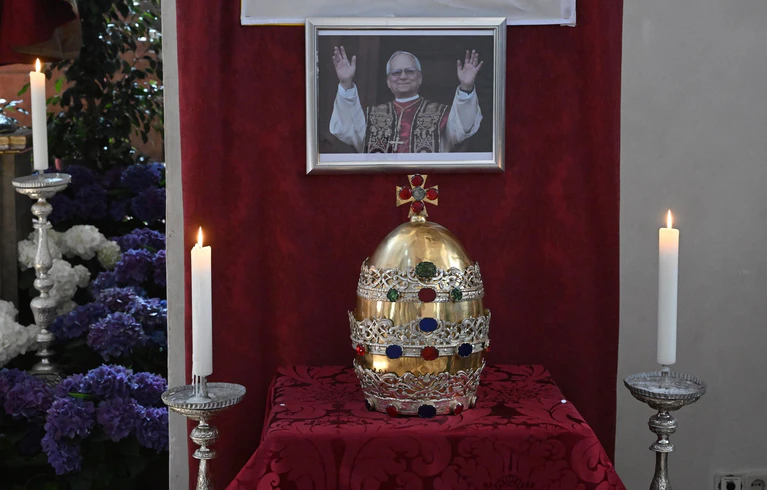 In der Münchner Stadtpfarrkirche ist die Tiara der Petrusfigur vor einem Bild des neuen Papstes Leo XIV. zu sehen. — © Felix Hörhager/dpa