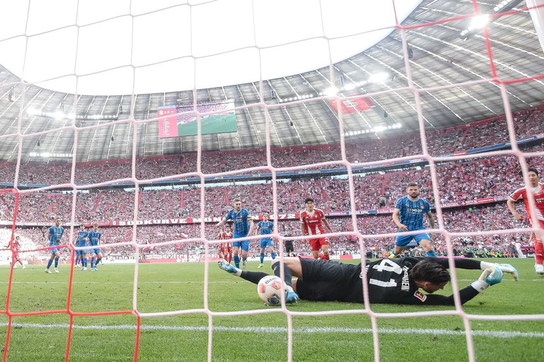 Nach dem Schuss von Michael Olise prallt der Ball vom Pfosten an den Fuß von Heidenheims Torwart Diant Ramaj und von dort zum 3:3 ins Tor.  — © Harry Langer/dpa