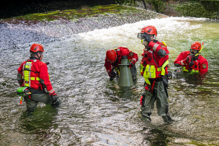 Taucher suchen nach dem Ablassen des Wassers am Bachgrund nach einer Unfallursache. (Archivfoto)   — © Peter Kneffel/dpa
