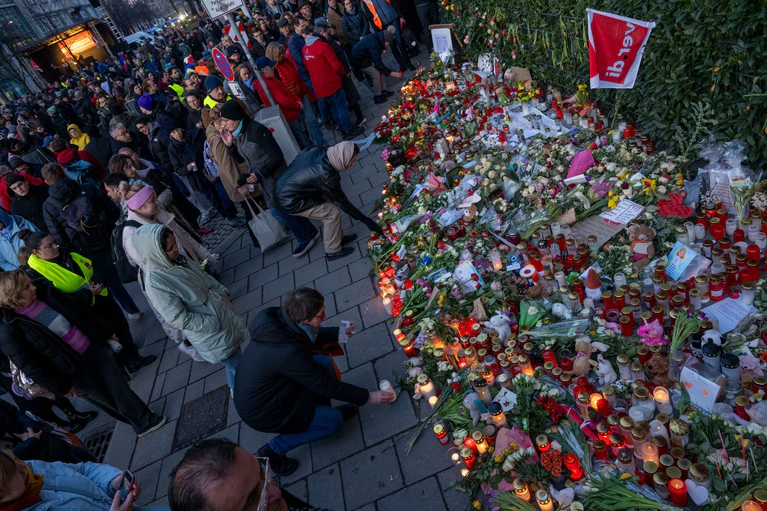 Teilnehmer einer Verdi-Gedenkveranstaltung für die Opfer des Anschlags auf eine Demonstration legen Kerzen, Blumen und Karten ab. — © Peter Kneffel/dpa