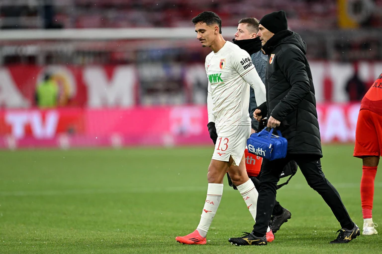 Augsburgs Verteidiger Dimitrios Giannoulis (l)  geht verletzt vom Platz. — © Sven Hoppe/dpa