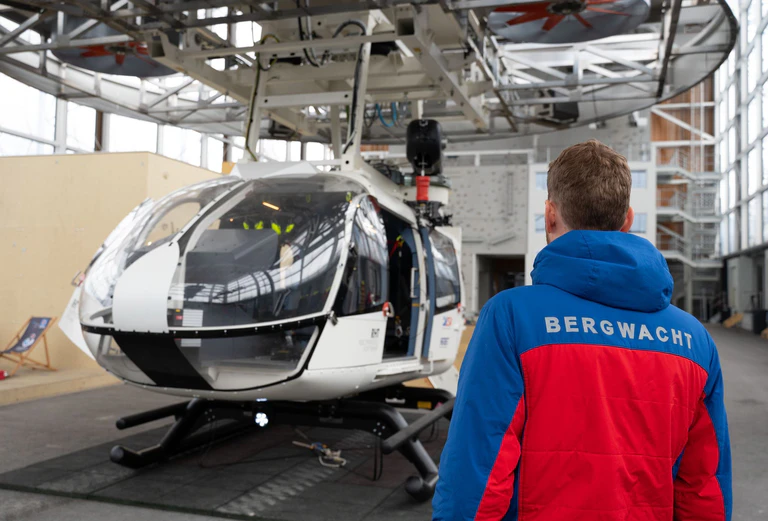 Im Bergwacht-Zentrum für Sicherheit und Ausbildung steht ein Mitglied der Bergwacht Bayern vor einem Hubschrauber-Modell. (Archivbild) — © Magdalena Henkel/dpa
