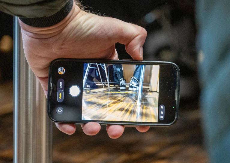 Eine Person fotografiert mit einem Smartphone die Fußfesseln, die der Angeklagte Halid S. im Gerichtssaal tragen muss. — © Stefan Puchner/dpa