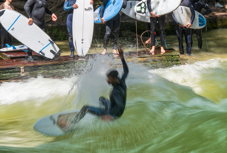 Endlich wieder mit dem Brett auf die Eisbachwelle - darauf hoffen Surferinnen und Surfer in München. (Archivbild) — © Peter Kneffel/dpa