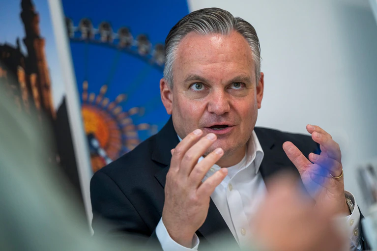 Münches neuer Wiesnchef Scharpf vor einem Foto des Riesenrades.  — © Peter Kneffel/dpa
