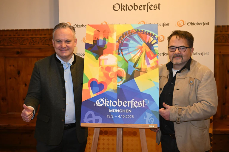 Der Designer Florian Huber zeigt mit Wiesnchef Scharpf sein Wiesn-Motiv.  — © Felix Hörhager/dpa