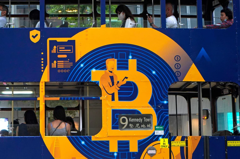 Eine Werbung für die Kryptowährung Bitcoin auf einer Hongkonger Straßenbahn. Kryptoanleger weltweit glauben laut einer Umfrage, dass es weiter aufwärts geht. (Foto: Illustration) — © Kin Cheung/AP/dpa