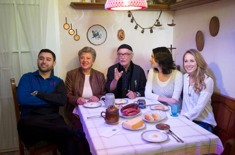 Die Schauspieler Hüseyin Ekici (Orkan Kortuglu), Marie-Luise Marjan (Helga Beimer), der Produzent der Fernsehserie «Lindenstraße», Hans W. Geißendörfer, und die Schauspielerinnen Daniela Bette (Angelina Buchstab) und Clara Dolny (Josi Stadler) sitzen in Speyer im Museum Wilhelmsbau am Technik Museum in der Originalkulisse der Wohnküche der «Lindenstraße»-Hausmeisterin Else Kling. — © picture alliance / dpa