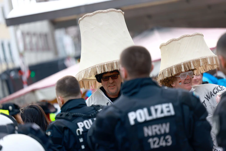Lampenschirmkostüme überragen in Köln die Ordnung schaffende Polizisten. (Archivbild). — © Rolf Vennenbernd/dpa