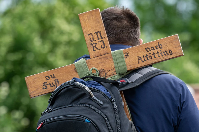 Ein Pilger trägt während der größten Fußwallfahrt Deutschlands ein Holzkreuz mit der Aufschrift «zu Fuß nach Altötting». — © Armin Weigel/dpa