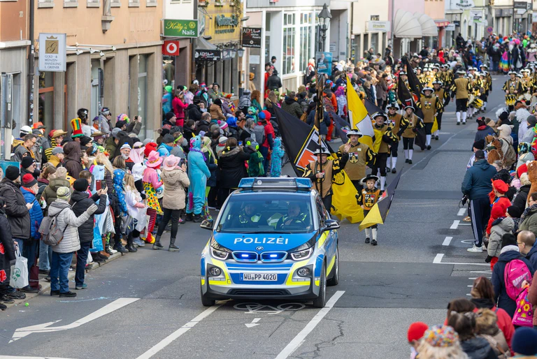 Erst das Polizeifahrzeug - dann die Närrinnen und Narren. — © Julien Becker/dpa