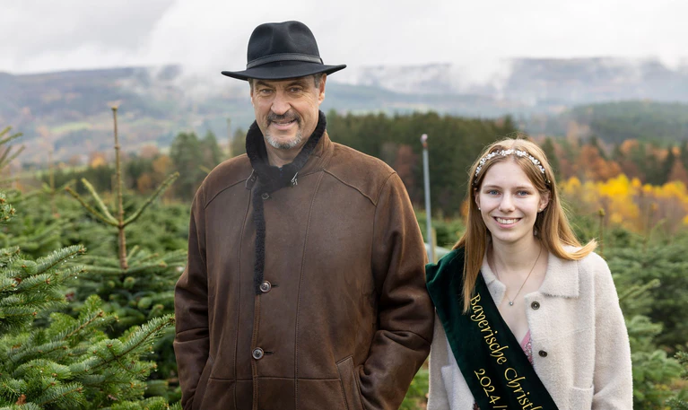 Ministerpräsident Markus Söder (CSU, l) schaute mit Christbaumkönigin Sina Klug im Christbaumdorf im unterfränkischen Mittelsinn vorbei. — © Heiko Becker/dpa