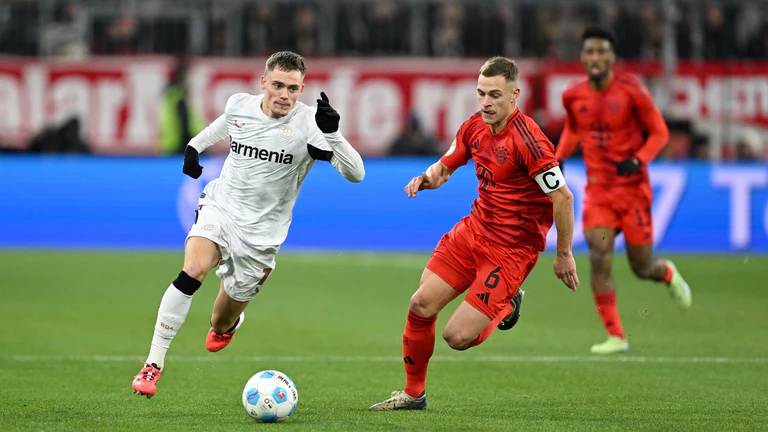 Nationalmannschafts-Kollegen im rasanten Duell: Leverkusens Florian Wirtz (l) und Bayerns Joshua Kimmich. — © Sven Hoppe/dpa